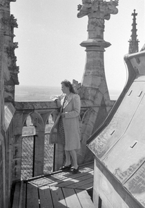 831661 Afbeelding van een vrouw die uitkijkt over de balustrade van de omloop bij de spits van de Domtoren (Domplein) ...